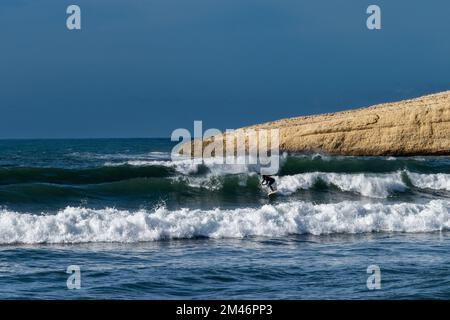 Santa Caterina di Pittinuri, Italy - 13 December, 2022: surfer enjoying good waves on the west coast of Sardinia during a good winter swell Stock Photo