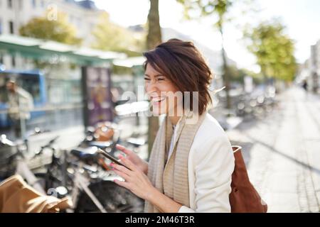 Smiling businesswoman using smart phone in street Stock Photo