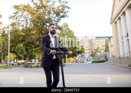 Businessman riding electric push scooter Stock Photo