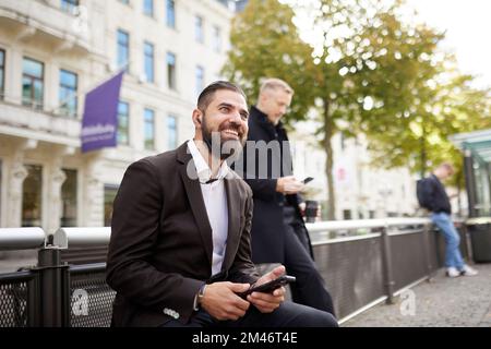 Smiling businessmen using phones in city Stock Photo