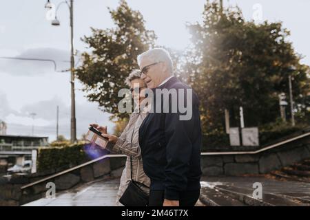 Senior couple using smart phone in city Stock Photo