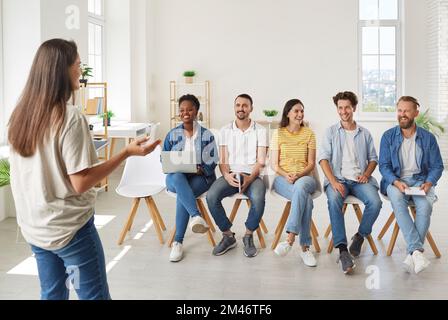 Smiling young startup colleagues talking and discussing ideas at casual meeting in bright office. Stock Photo