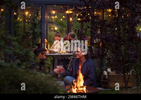 Friends sitting at fire in garden Stock Photo