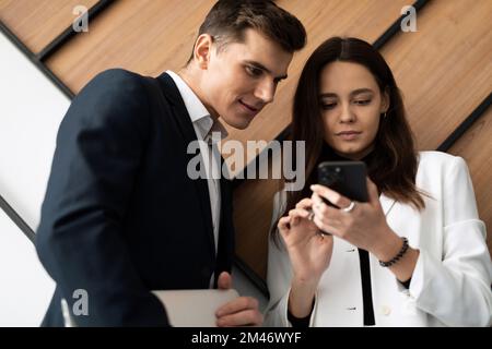 colleagues man and woman communicate during a break demonstrating a mobile phone Stock Photo