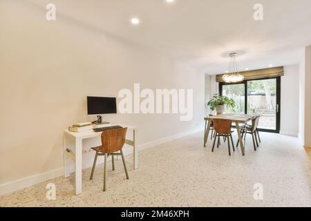 a living room with a desk and chair in front of an open door that leads out to the patio area Stock Photo