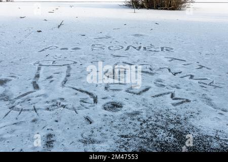 Frozen pond with rude words and pictures showing some people are not heeding warnings of danger of walking on frozen lakes, UK, December 2022 Stock Photo