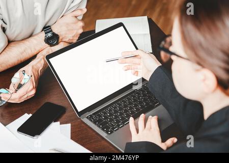 Blank screen of laptop on job desk in office and two business people. Stock Photo