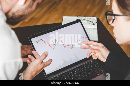 Business people working together analyzing the cryptocurrency chart on the laptop display. Stock Photo