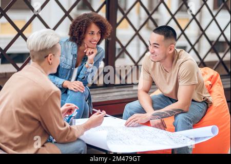 Architectural team engaged in discussing a technical drawing Stock Photo