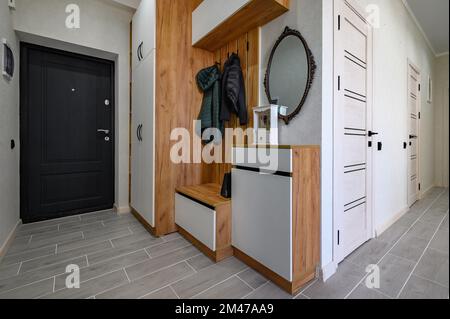 Small entrance hallway interior with shoe storage, hanger stand and mirror Stock Photo