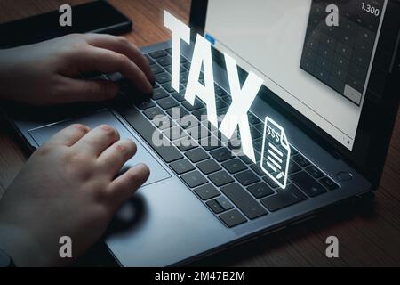 Business woman using calculator on laptop for do math finance with VR word TAX. Data analysis, paperwork, financial research, report. Stock Photo