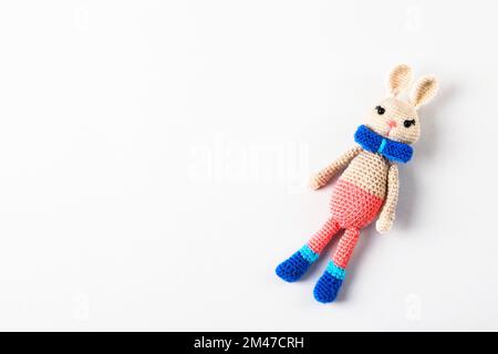 Knitted children's toy hare or rabbit on a gray background. The symbol of 2023. Stock Photo