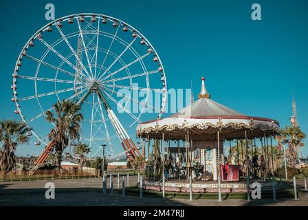 Ferris wheel and empty rides in old vintage amusement park without people. Stock Photo