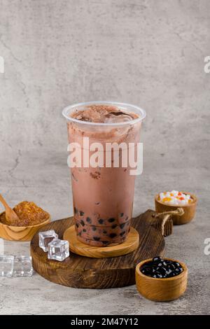 Boba or tapioca pearls is taiwan bubble milk tea in plastic cup with dark chocolate flavor on texture  background, summers refreshment. Stock Photo