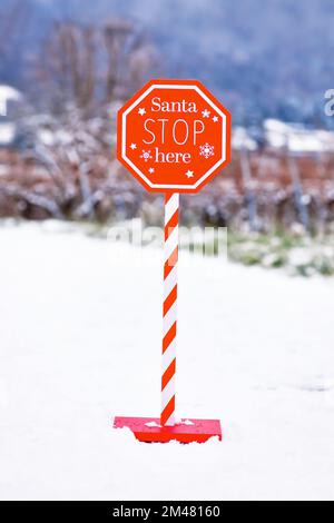 Christmas sign with text 'Santa Stop here' in snowy landscape Stock Photo