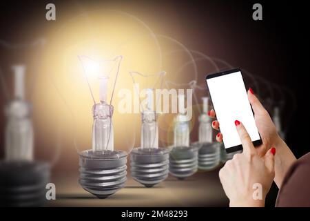 Controlling light bulb temperature and intensity with a smartphone application. Concept of a smart home and managing light with mobile devices. Stock Photo