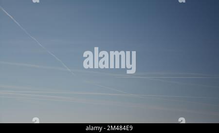 Chemtrail or contrail formations after airplane traffic forming pollution in the blue sky. Modern times phenomenon. Stock Photo