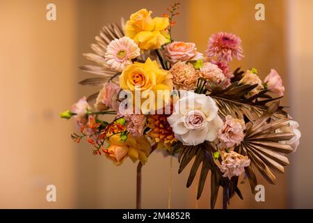 Beautiful flower composition with dry palm leaves, gerberas, white and yellow roses, carnations. Autumn arrangement for decorating party, home or tabl Stock Photo