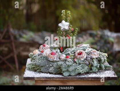 Handmade Christmas wreath for wild birds decorated with rose hip berries, apple and mini bundt cakes, birds feeder made from organic peanuts, birdseed Stock Photo