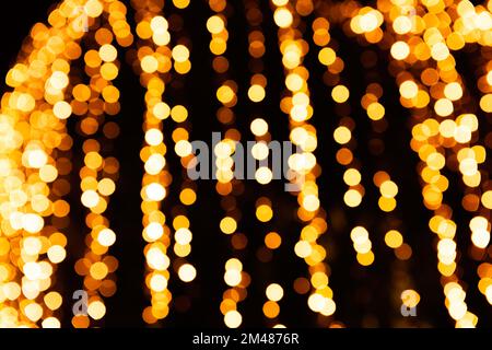 Festive bright blurred golden background. On Christmas black curtain, yellow bokeh lights are shining out of focus. Blank for postcards, place for tex Stock Photo
