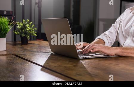 Hands working at laptop in modern office, works at PC computer at wood desk. High quality photo Stock Photo