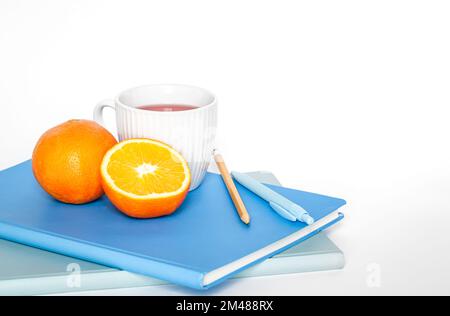 A cup of tea, orange and notebooks on a white background isolated, copy space. Stock Photo