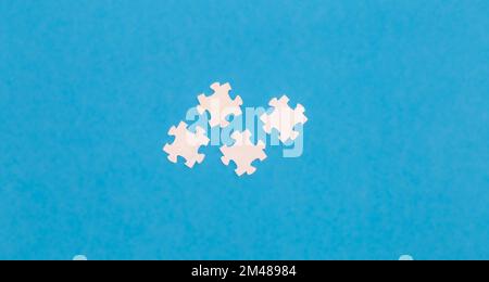 White puzzles on a blue background, flat lay. Stock Photo