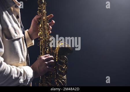 Saxophone in the hands of a man on a dark background, copy space. Stock Photo
