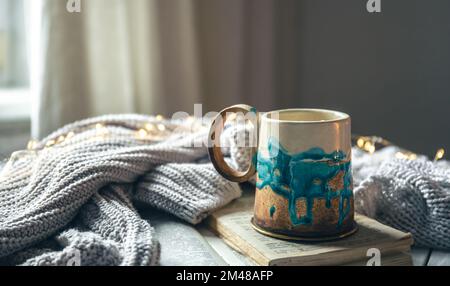 Beautiful handmade ceramic cup on a blurred background with a knitted element. Stock Photo