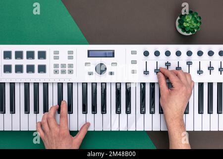 Hands of a man playing musical keys on a colored background, flat lay. Stock Photo