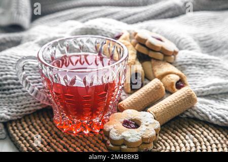 A cup of red tea and cookies on a blurred background with a knitted element. Stock Photo
