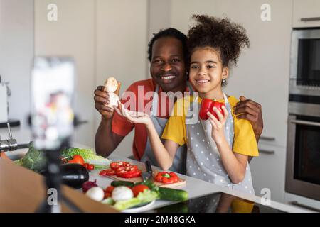 Culinary Blog. Happy Black Man And His Daughter Recording Video In Kitchen Stock Photo