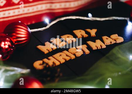 Gingerbread words Merry Christmas on old black table with Christmas decorations Stock Photo