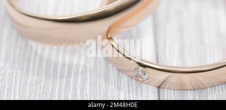 Two wedding gold rings lie on a white wooden table, close-up. 3D rendering.. Stock Photo