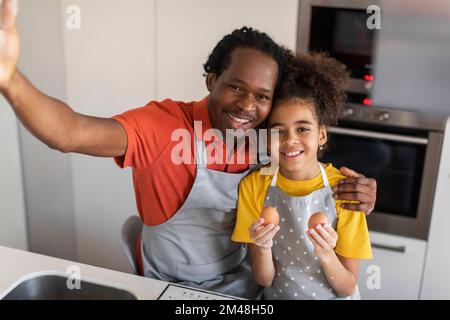 Happy Black Father And Cute Preteen Daughter Taking Selfie In Kitchen Stock Photo