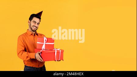 Happy Young Arab Man Holding Gift Boxes And Winking At Camera Stock Photo