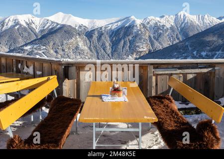 Table and benches with skins in a mountain cafe overlooking the snow ...
