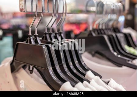 Row of coat hangers on a retail store shelf.  Stock Photo