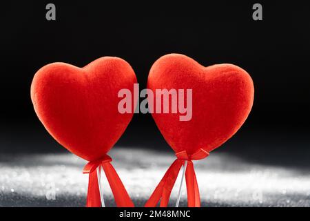 Valentine's Day, two red loving hearts on a black background with sequins. Stock Photo
