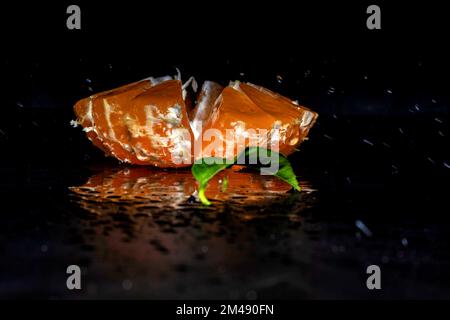 Cut tangerine with splashes of water on a black background Stock Photo