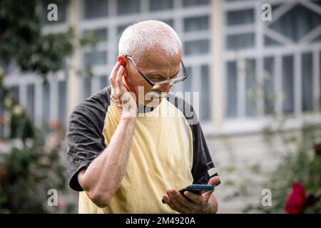 An old man on the advice of an online assistant clicks on the dots on the body for self-help for neurological diseases or other therapeutic problems Stock Photo