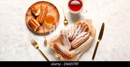 Composition with sweet eclairs, hot tea and honey on light background, top view Stock Photo