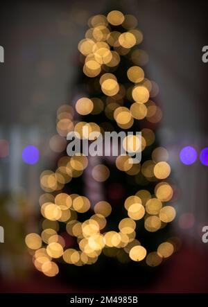 Defocused Christmas tree with bokeh fairy lights glowing. Abstract blur of Christmas tree shape Stock Photo