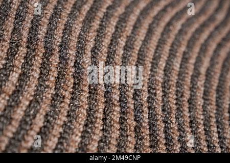 Dark relief carpet texture with asymmetric rows for unusual background. Close up view of strip pattern of synthetic tight wavy rows. Concept of textures and background. Stock Photo