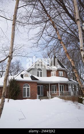 Red brick with grey and white trim new Victorian cottage style home in winter. Stock Photo