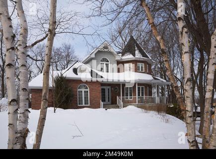 Red brick with grey and white trim new Victorian cottage style home in winter. Stock Photo