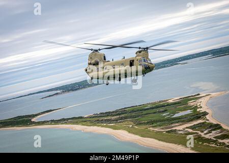 A Connecticut National Guard CH-47 Chinook helicopter flies to Nantucket Island to refuel after delivering a 14,000-pound buoy that broke free from its mooring to U.S. Coast Guard Cutter Oak (WLB 211) June 1, 2022. The Connecticut National Guard has assisted the Coast Guard in similar missions the past few years because of the lift capabilities of its CH-47 fleet. Stock Photo