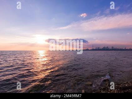 Autumn sunset view across Toronto Harbour of Lake Ontario with foggy Downtown Toronto skyline in the background under the blue sky with pink clouds Stock Photo