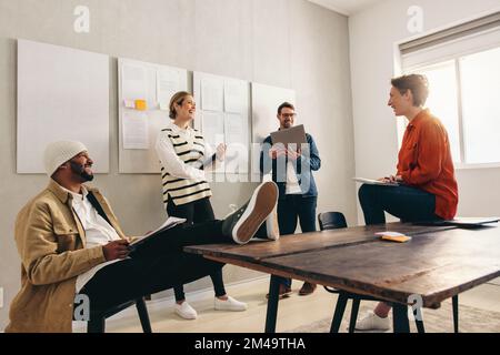 Happy business colleagues smiling cheerfully during a meeting in a creative office. Group of diverse businesspeople having a discussion while working Stock Photo