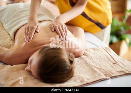 Hands of masseuse spreading oil on back of client Stock Photo
